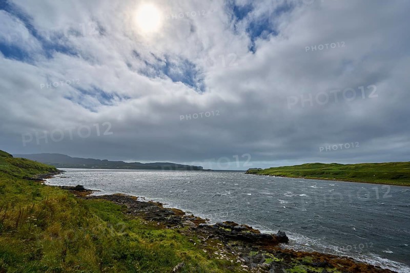 Cloudy sky over an estuary, sun shining through, grassy and rocky coast, Isle of Skye, Scotland, United Kingdom, Great Britain