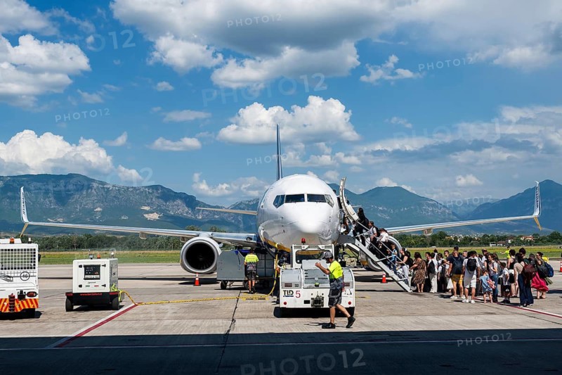 TIRANA, ALBANIA - JULY 3, 2026: Passengers boarding commercial passenger aircraft on airport apron, showcasing air travel, boarding process and modern aviation with mountain scenery