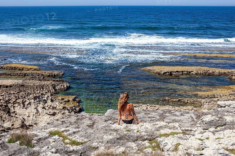 Middle aged woman contemplates the cantabric sea at the San Vicente cliffs along the coast trail near San Vicente de la Barquera, Santander, Cantabria, Spain