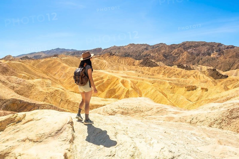 Woman traveler exploring the unique geology and expansive desert landscape of zabriskie point in death valley national park, enjoying an outdoor adventure