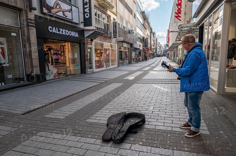 Effects of the coronavirus crisis, empty shopping street, lonely street musician, around 1400 on Saturday, normally thousands of people go shopping here at this time, Hohe Straße in Cologne, Germany