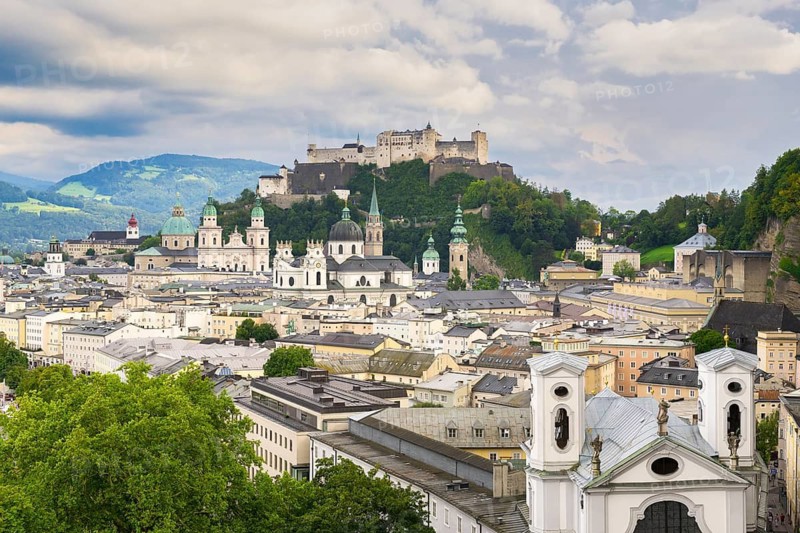 View of Salzburg with Hohensalzburg Fortress in the background and the historic city centre in the foreground, surrounded by mountains under a cloudy sky, Salzburg, Salzburger Land, Austria