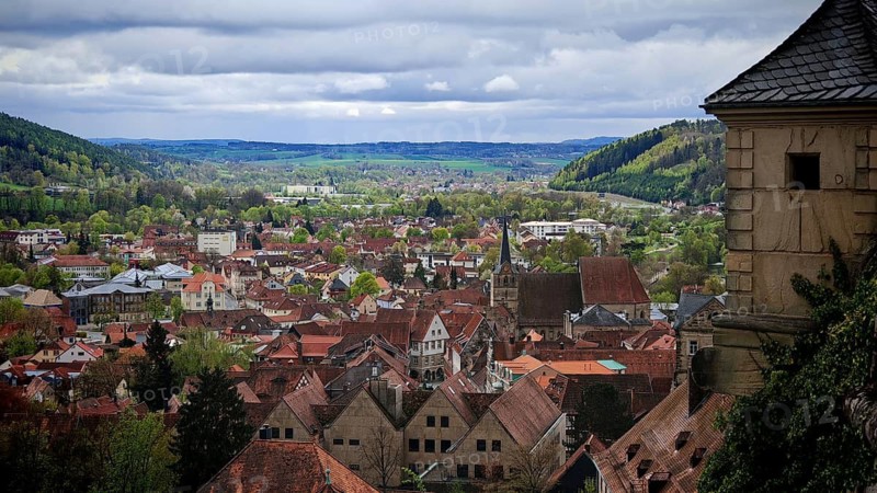 View from the fortress over Kronach with surrounding green hills in spring and cloudy sky, Veste Rosenberg, Kronach, Frankenwald nature park Park, Upper Franconia