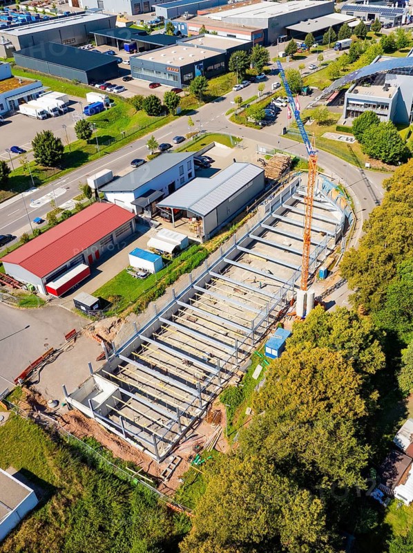 Aerial view of an industrial building with crane and various buildings in an urban area, Parkhaus Bau, Calw, Germany