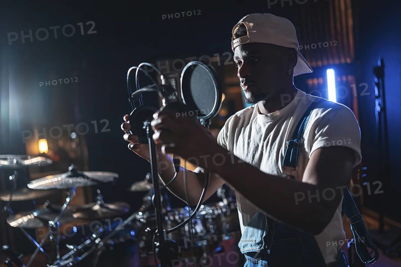 Young african american artist adjusting microphone, preparing to record a new album in a music studio