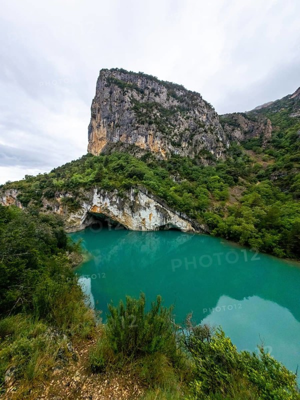 Entremon gorge's towering cliffs and lush green slopes frame the vivid turquoise cinca river as it winds through the huesca pyrenees, a dramatic untouched mountain canyon landscape
