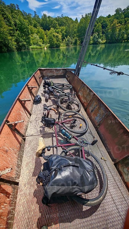 Two bikes on an old crank ferry across the Mreznica river in a quiet, green natural landscape, cycling in Croatia