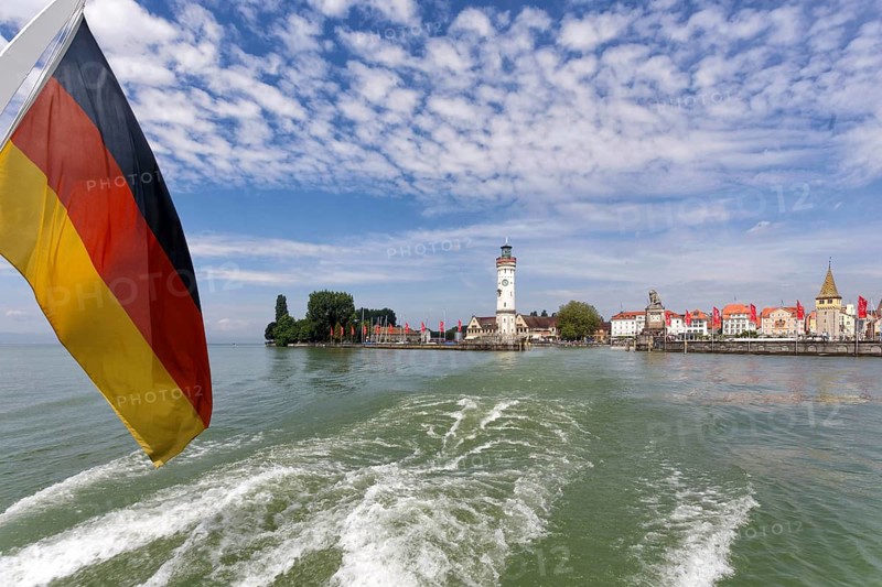 Lighthouse and harbour entrance, passenger ship with Germany flag, Lake Constance, Lindau, Bavaria, Germany