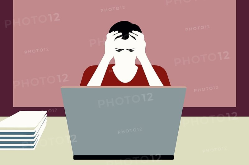 An illustration shows a person seated at a desk with a laptop, visibly stressed and overwhelmed, holding their head in frustration. Paperwork stacks nearby indicate a heavy workload