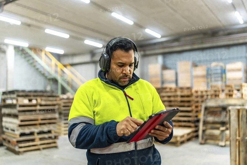 Worker using digital tablet while arranging pallets to reuse in a recycling plant
