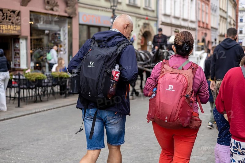 Krakow, Poland, 23.08.2025: A man and a woman walk together in Krakow, Poland. The man is middle-aged with short blond hair, wearing a dark jacket and shorts