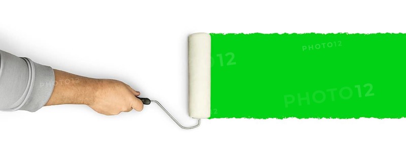 Male hand rolling paint roller over green screen background