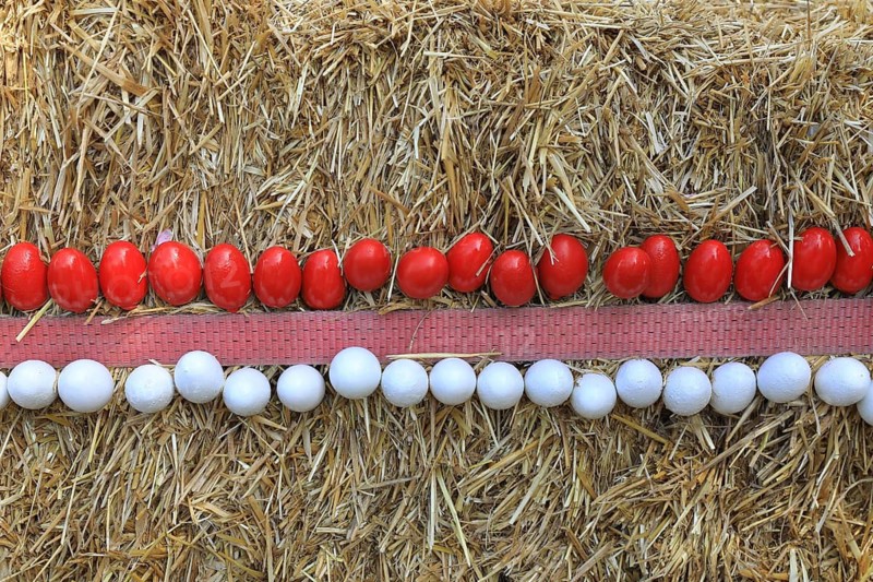 Easter decoration, Franconian Switzerland, Easter fountain, here in the district of Bamberg, Upper Franconia, Bavaria, Germany, decoration, Easter eggs in white and red in series on a straw background, decoration made of straw with red and white pearls in parallel rows, rustic feel