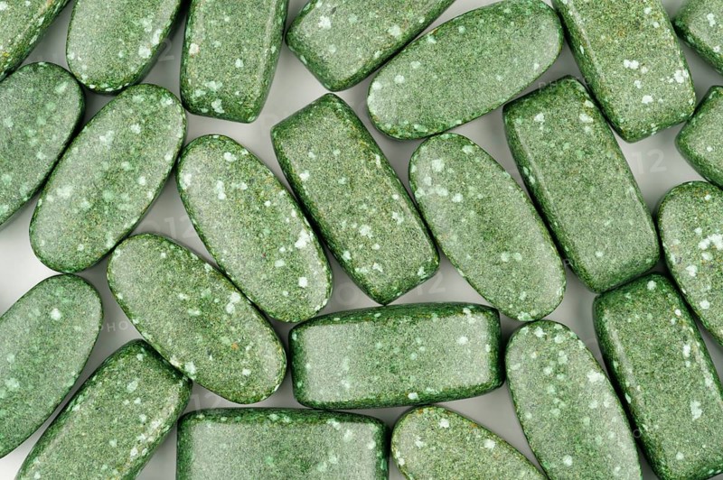 Close-up of green pills scattered on white background