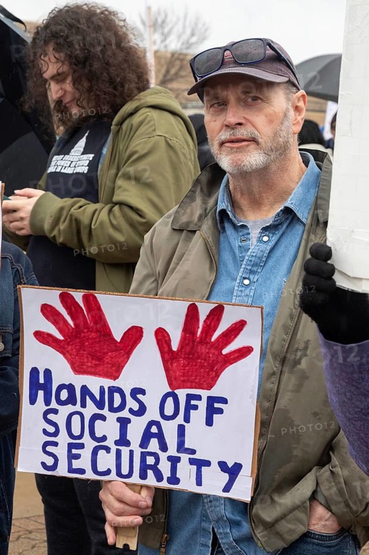 Troy, Michigan USA - 29 March 2025 - People gathered in the rain outside the Tesla Showroom at the Somerset Mall to protest Tesla owner Elon Musk's role in slashing government services. It was one of many 'Tesla Takedown' actions planned around the country and abroad