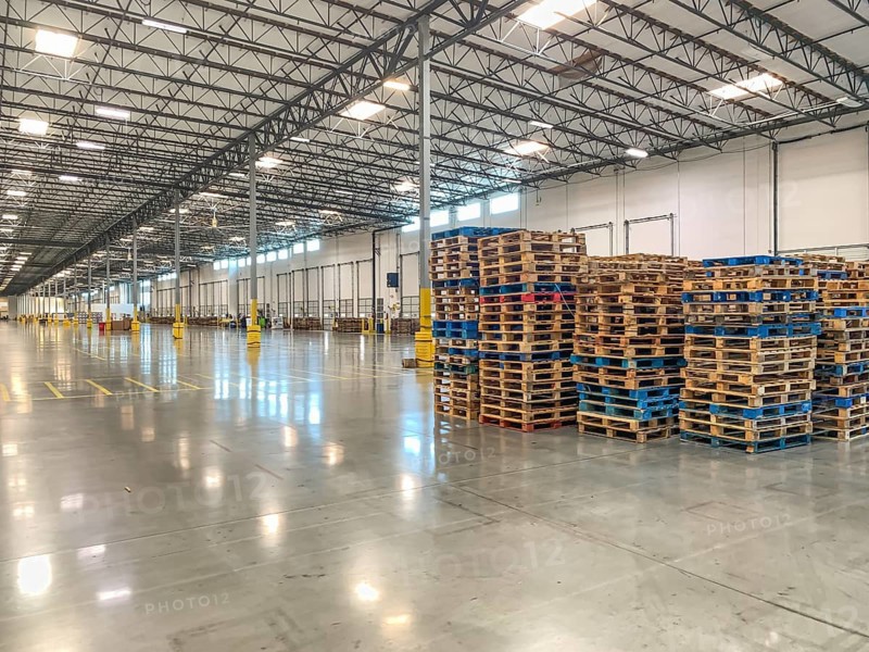 Massive Empty Industrial Warehouse Interior With Stacked Pallets