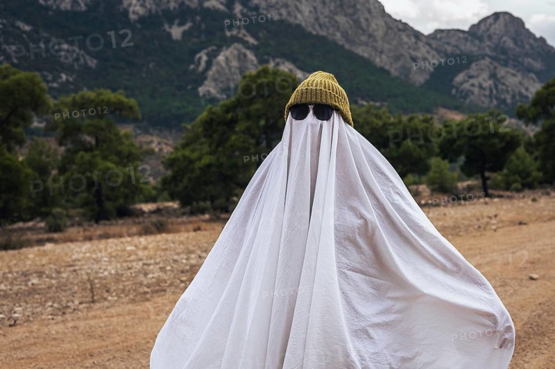 Minimal Halloween celebration with person wearing a ghost costume in nature. Cozy seasonal mood, simple traditions and slow lifestyle concept.