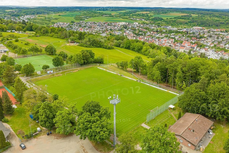 Green sports fields in a rural area with surrounding fields and a village, Sportplatz Aidlingen, Böblingen district, Germany