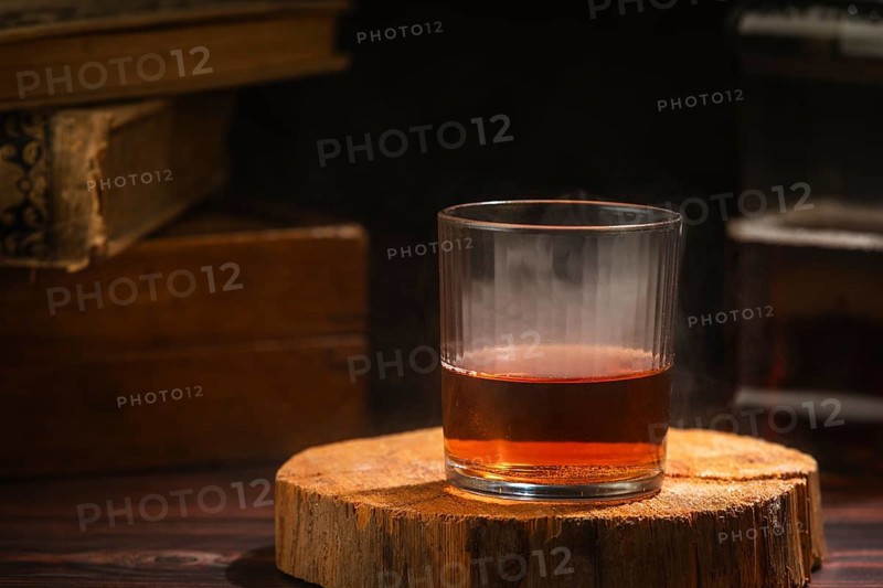 Glass of whiskey with light steam on wood in a cozy setting