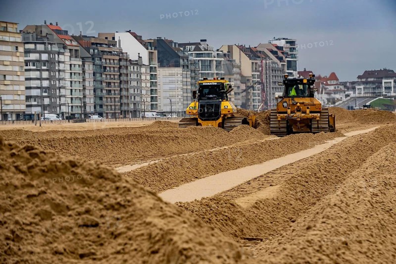 Bulldozers when distributing sand on the beach in the town of Knokke-Heist, part of coastal protection and beach maintenance, due to floods, erosion and sea level rise, the sand on the beach is repeatedly washed into the sea, in winter the sand from the seabed is washed back onto the beach with suction vessels, the excavators and levelers then distribute the sand back on the beach to eliminate the difference in height so as to bathe To make the beach usable again for the next season