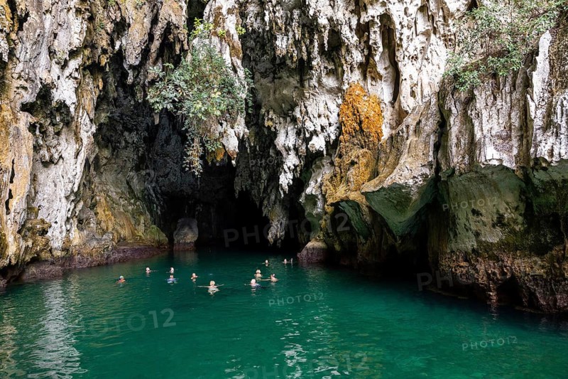 Tourists enjoy the refreshing turquoise waters inside a stunning limestone cave in Indonesia. Natural formations surround the serene scene, creating an atmosphere of adventure and tranquility