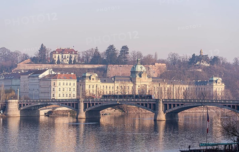 A serene morning scene captures the historic essence of Prague, featuring the majestic cityscape with its iconic bridges and elegant architectural structures alongside the calm waters