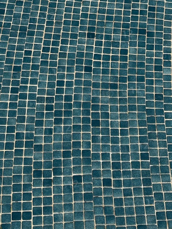 This image showcases an irregular blue mosaic pattern made of small square tiles. The textured design creates a wavy effect, adding depth and visual interest to the surface