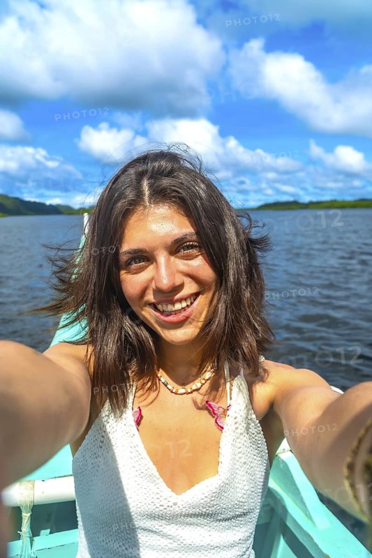 Young woman taking a selfie while enjoying a boat trip in a traditional banca boat in siargao island, philippines