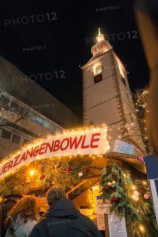 A Christmas market stall in front of an illuminated church at night, Christmas market, Nagold, Black Forest, Germany