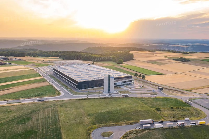 Large industrial plant nestled in vast fields at sunset, Eisberg, Nagold, Germany