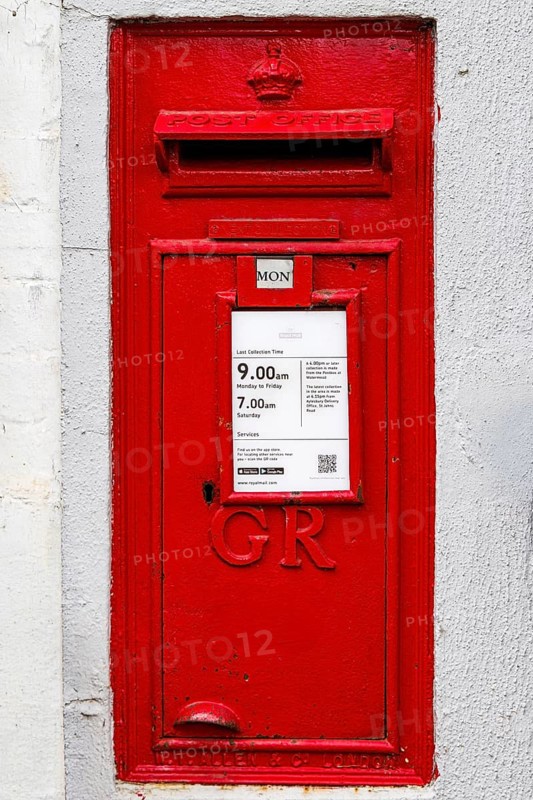 Red wall mounted Royal Mail postbox bearing the GR royal cipher, collection times displayed, Bierton, Buckinghamshire, United Kingdom