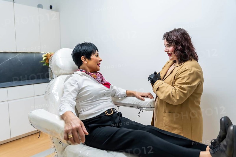 Patient consulting with a female doctor about skin care options and cosmetic procedures while sitting on a chair in a modern aesthetic clinic, discussing beauty and wellness