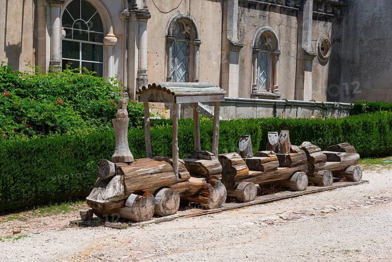 Ein handgemachter Holzzug steht vor einem antiken Gebäude mit verzierten Fenstern und grünen Hecken, Mata Nacional do Buçaco, National-Wald von Bussaco, Bucaco, Mealhada, Beira Litoral, Portugal