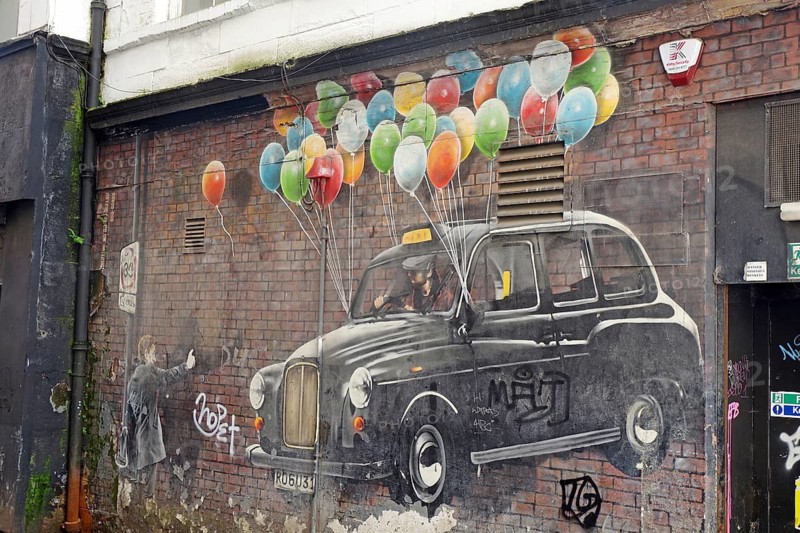 A mural shows a taxi being lifted into the air by colourful balloons and a child, Fantasy, Mural Trail, Glasgow, Scotland, United Kingdom