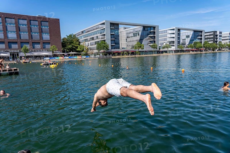 The Duispool, the outdoor harbor pool in Duisburg's inner harbor, in the back harbor basin has become a pop-up outdoor pool for the 2nd time, temporarily during the summer holidays, surrounded by industrial monuments, people can swim in a restricted area, there are swimming islands, lifeguards watch out, admission is free, North Rhine-Westphalia, Germany