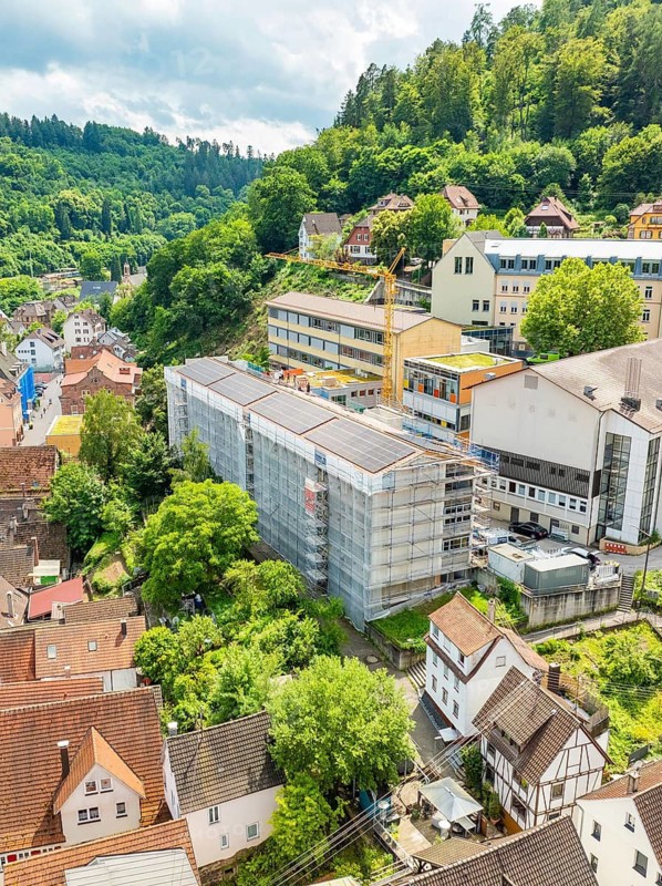 Urban landscape with construction crane and buildings in lush green surroundings, new PV plant at Heinrich-Immanuel-Perrot secondary school, city of Calw, Germany