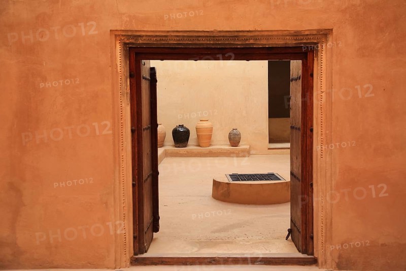 View through door opening of courtyard with jugs and minimalistic wall decoration, courtyard, Fort Nizwa, Ad Dakhiliyah, Oman