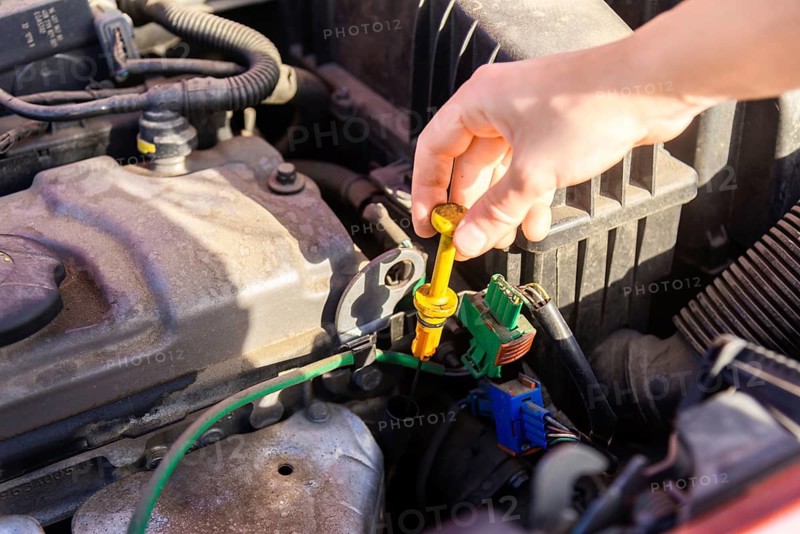 A person checks the oil level in a car engine after an accident, ensuring vehicle safety and maintenance The image highlights the importance of regular checks after collisions