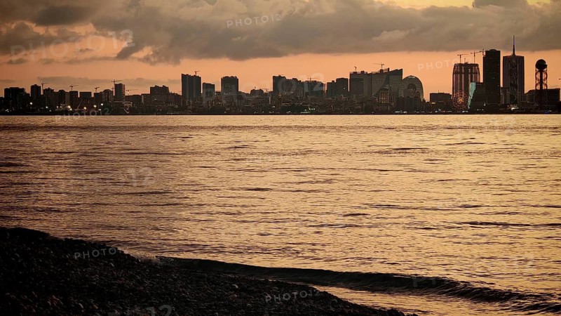Melancholy cityscape at dusk with a view of a quiet river and pebble beach, Batumi, Georgia