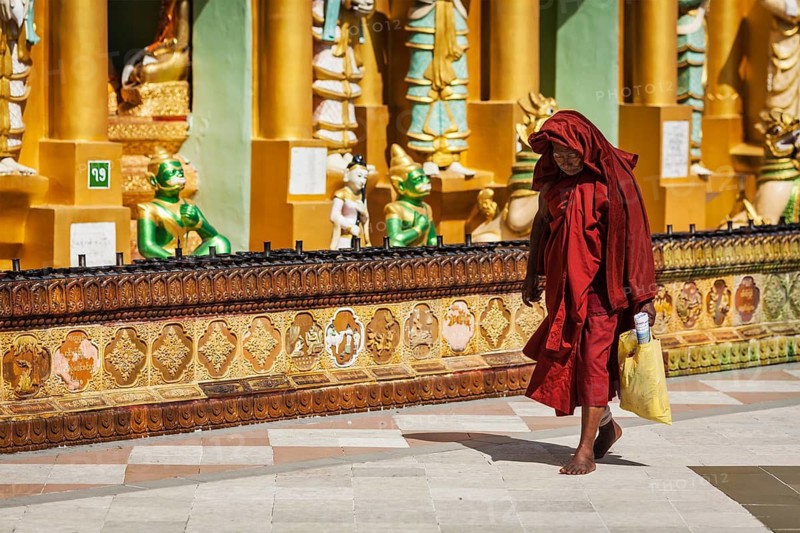 YANGON, MYANMAR, JANUARY 3, 2014: Old Buddhist monk walking in Shwedagon Paya pagoda, the most sacred Buddhist pagoda in Myanmar
