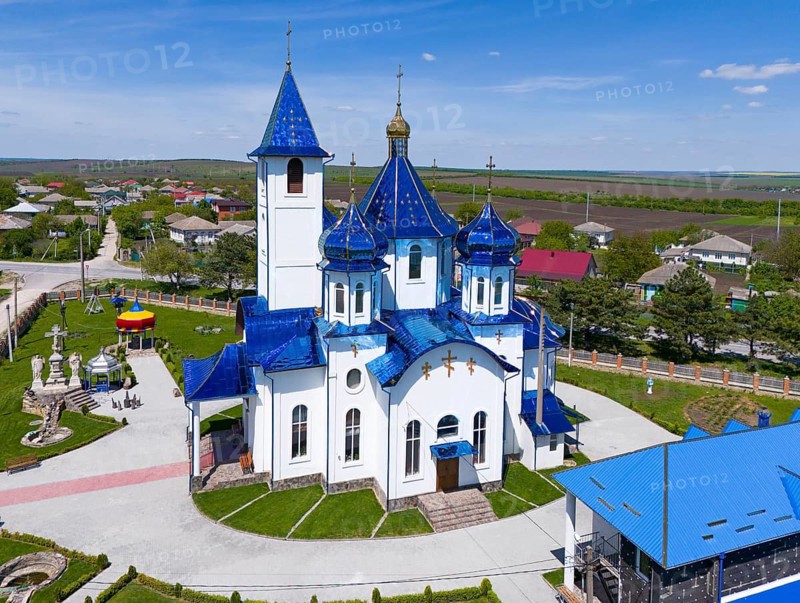 Church with blue roof and white facades, surrounded by a village and numerous trees, on a sunny day, aerial view, Church of the Protection of Our Lady, Biserica Acoperamântul Maicii Domnului, Tarigrad, ?arigrad, Drochia district, Republic of Moldova, Moldova