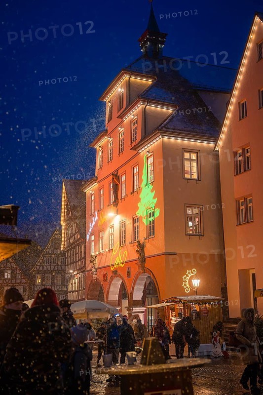 Christmas-lit old town buildings at a winter market at night, people strolling in the snow, Christmas market Calw, Black Forest, Germany