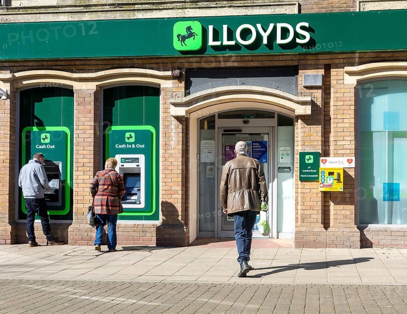 People using ATM cash machine at branch of Lloyds Bank, Lowestoft town centre, Suffolk, England, UK