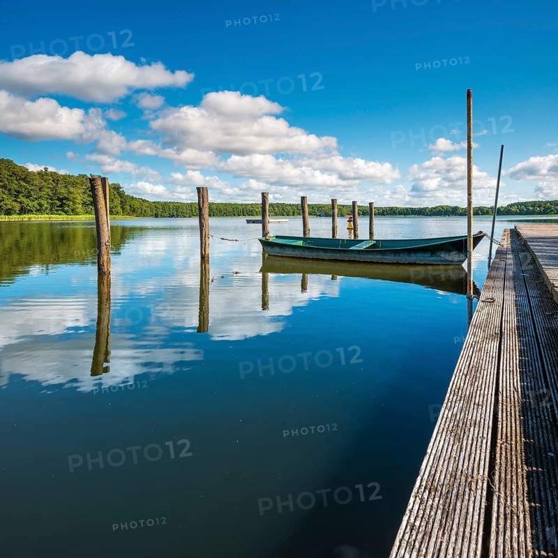 Jetty with rowing boats at Moderfitzsee under blue sky with cumulus clouds in summer, Himmelpfort, Brandenburg, Germany
