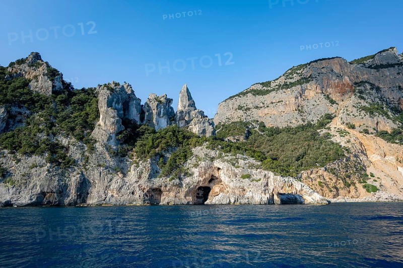 Picturesque rocky coast, cliffs with caves in the morning light, L'Aguglia rock peak, blue sea and Cala Goloritzé beach, Golfo di Orosei, Baunei, Sardinia, Italy