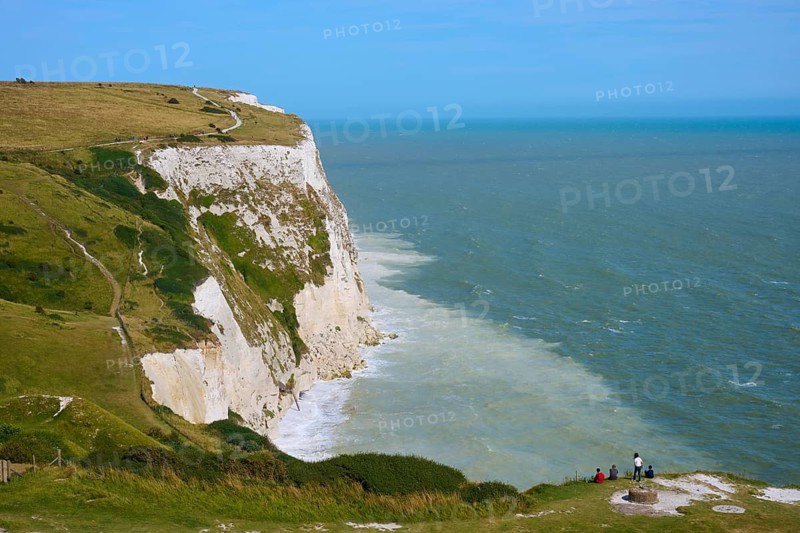 Wide view of white cliffs merging into ocean, people standing near edge, summer, chalk cliffs, English Channel, Dover, Kent, England, United Kingdom