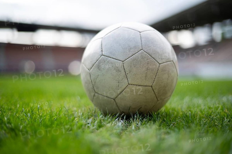 White soccer ball lying on the grass at stadium in Lubin, Poland