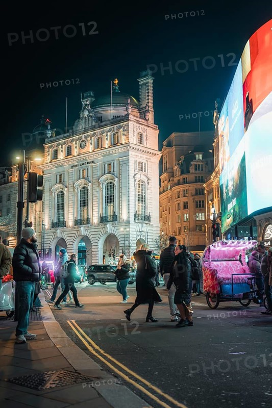 Glowing city at night, buildings illuminated by lights, people and billboards, New Year's Eve London, United Kingdom