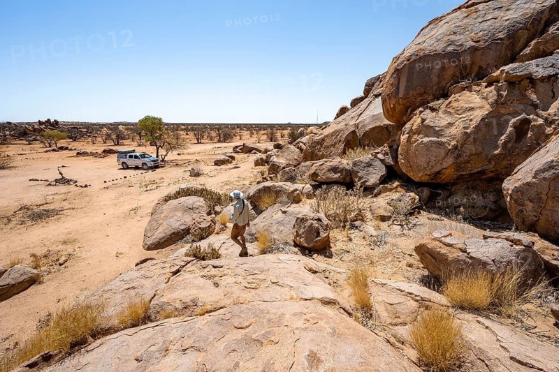 Young man between hills with round smooth rocks, Damaraland, Kunene, Namibia
