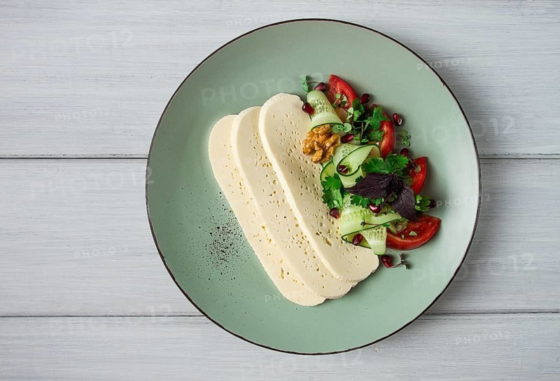 Sliced Imeruli cheese, Georgian cheese, with vegetables, top view, no people